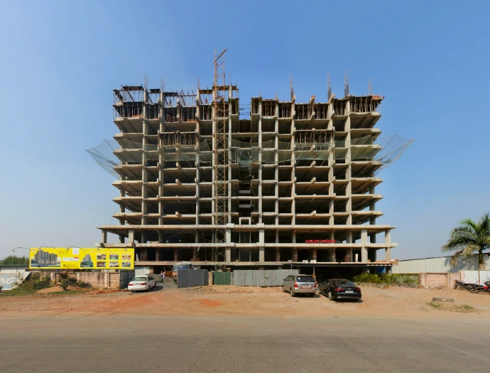 a large building under construction with cars parked in front of it